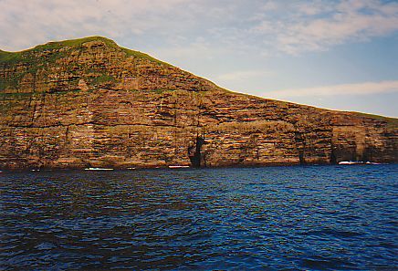 Picture of steep cliffs with a cave only accessible from the sea at the bottom