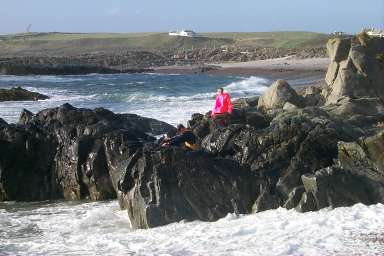 Picture of kids in waterproofs on rocks at the sea