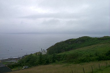 Picture of a view over the sea with the bottom of a mountain range just visible under clouds