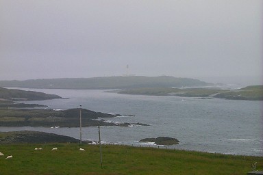 Picture of a shoreline and a few island with a lighthouse in the distance