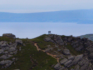 Picture of the silhouette of two walkers on a ridge