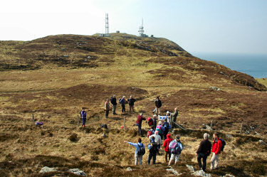 Picture of people climbing over a fence, aerial masts in the background