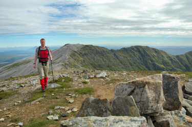 The author approaching the summit of Conival, Ben More Assynt in the background Picture of a walker (Armin) approaching with further hills in the background