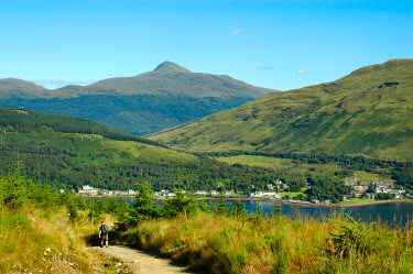 Picture of a mountain behind lower mountains and a loch