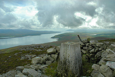 Picture of a trig point on a hill with a sound behind it