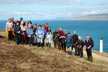 Picture of a group of walkers with a lighthouse in the background