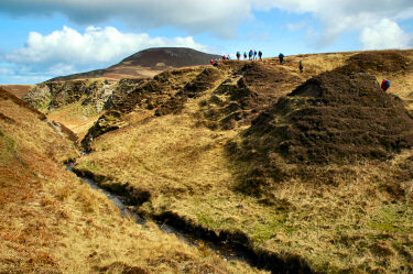 Picture of walkers leaving a deep cut towards a hill