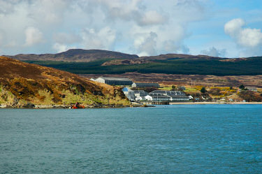 Picture of a distillery at a shore, a shipwreck also in view