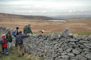 Picture of walkers climbing over a drystone wall