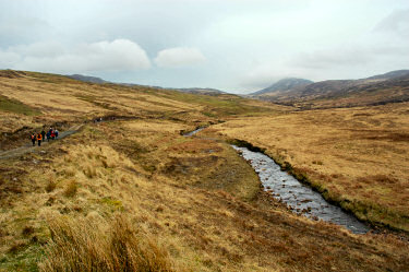 Picture of walkers on a track next to a burn