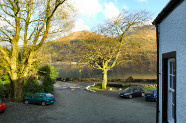 Picture of a view over a car park, a loch and some hills behind it