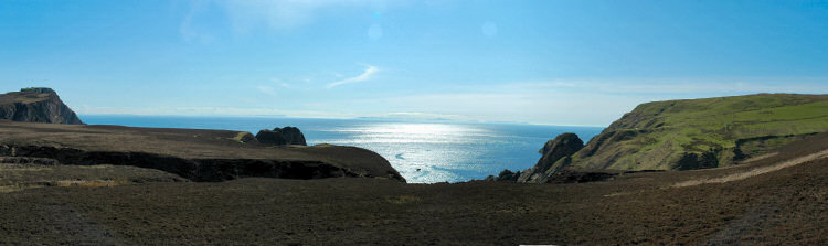 Picture of a view looking back over the cliffs and out to the sea glistening in the sun