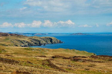 Picture of a view over a coastal landscape, a distillery and a small island in the distance