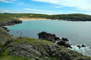 Picture of a bay with a beach at the end, sun breaking through (Lossit Bay, Islay)