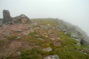 Picture of a trig point at a summit in low clouds