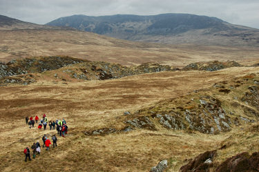 Picture of a group of walkers in wild terrain, a large mountain in the background