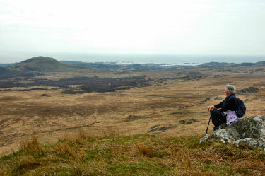 Picture of a woman sitting on a rock over a wide landscape