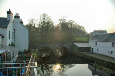 Picture of the morning sun over a river through a small village