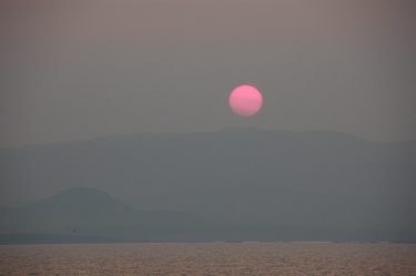 Picture of a sunset in very hazy skies over an island
