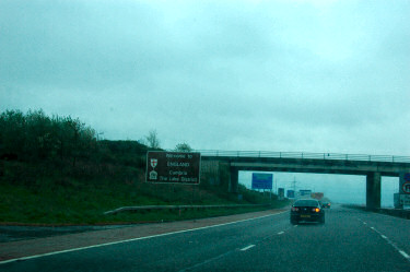 Picture of a 'Welcome to England' motorway sign in the rain