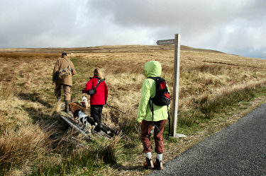 Picture of three walkers turning off at a sign reading Evans Walk