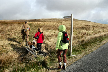 Picture of three walkers turning off at a sign reading Evans Walk