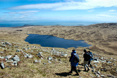 Picture of a view over a loch (lake) in a glen (valley), walkers in the foreground