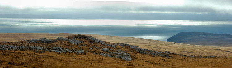 Picture of the sun breaking through over a sound between an island and the mainland