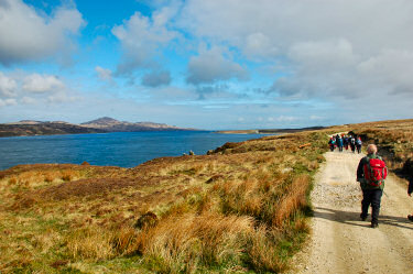 Picture of walkers on a wide track along a sound between two islands