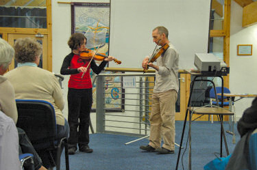 Picture of a girl and a young man playing violins