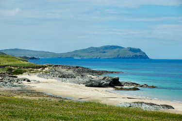 Picture of a view along a shoreline with a bay and cliffs in the distance