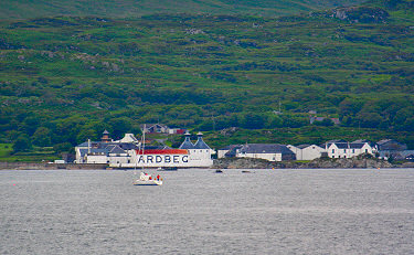 Picture of Ardbeg distillery from the sea, a sailing yacht in the foreground