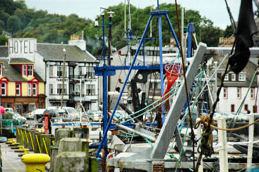 Picture of fishing boat masts in a harbour, a hotel in the background