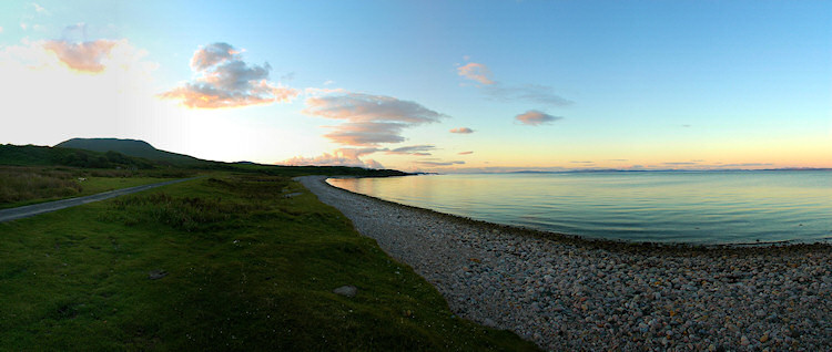 Picture of a panoramic view over a wide bay with a pebble beach in the evening light