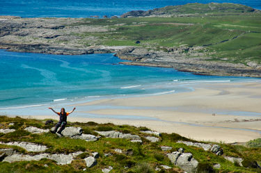 Picture of a woman sitting on rocks high above a beach