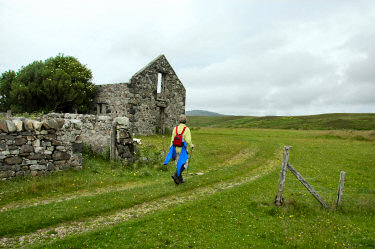 Picture of a woman walking past ruins of farm buildings