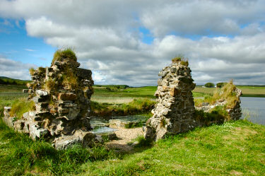 Picture of the ruins of a building, graveslabs sheltered by glass panes inside