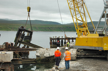 Picture of a crane lifting a part of an old pier