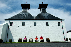 Picture of a family in whisky cask chairs in front of a distillery