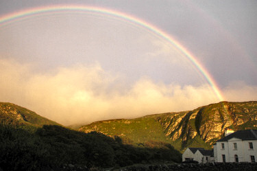 Picture of a bright rainbow above a house and crags
