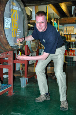 Picture of a man having filled a bottle of whisky from a cask