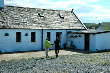 Picture of two women walking towards the entrance of a shop in a croft building