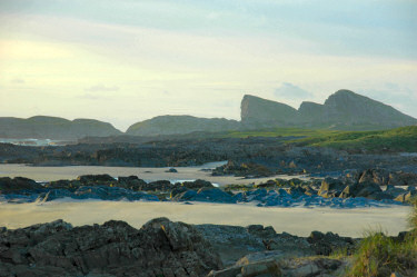 Picture of a view along a beach with some distinctly shaped rocks in the distance
