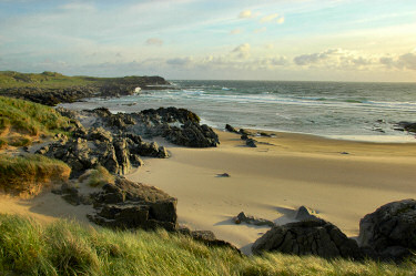Picture of a bay with a golden sandy beach as well as rocky cliffs