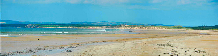 Picture of a panoramic view over a long sandy beach with some low dunes