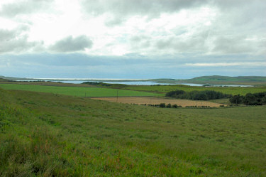 Picture of a loch (lake) with the sun breaking through clouds above