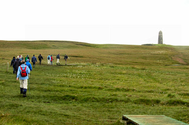 Picture of a group of walkers following a vague path towards a monument