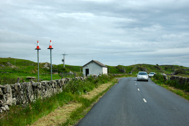 Picture of a road with two poles topped with traffic cones next to it