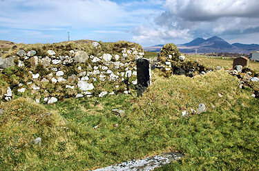 Picture of the remains of an old chapel, headstones standing and in it