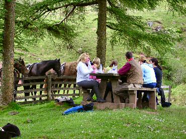 Picture of riders having a picnic, horses in the background